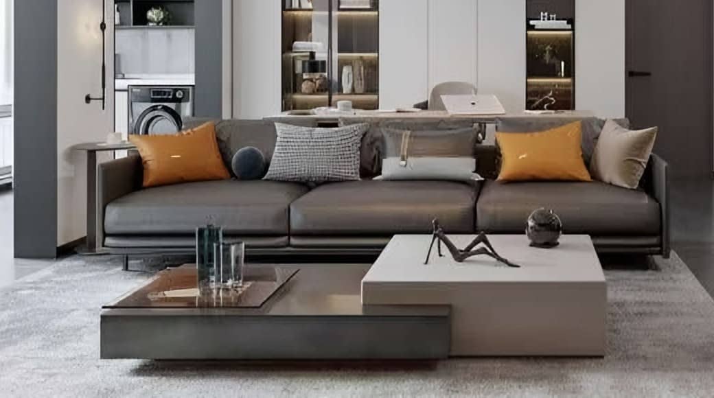 Grey three-seat sofa with ochre cushions and stacked stone and timber coffee tables