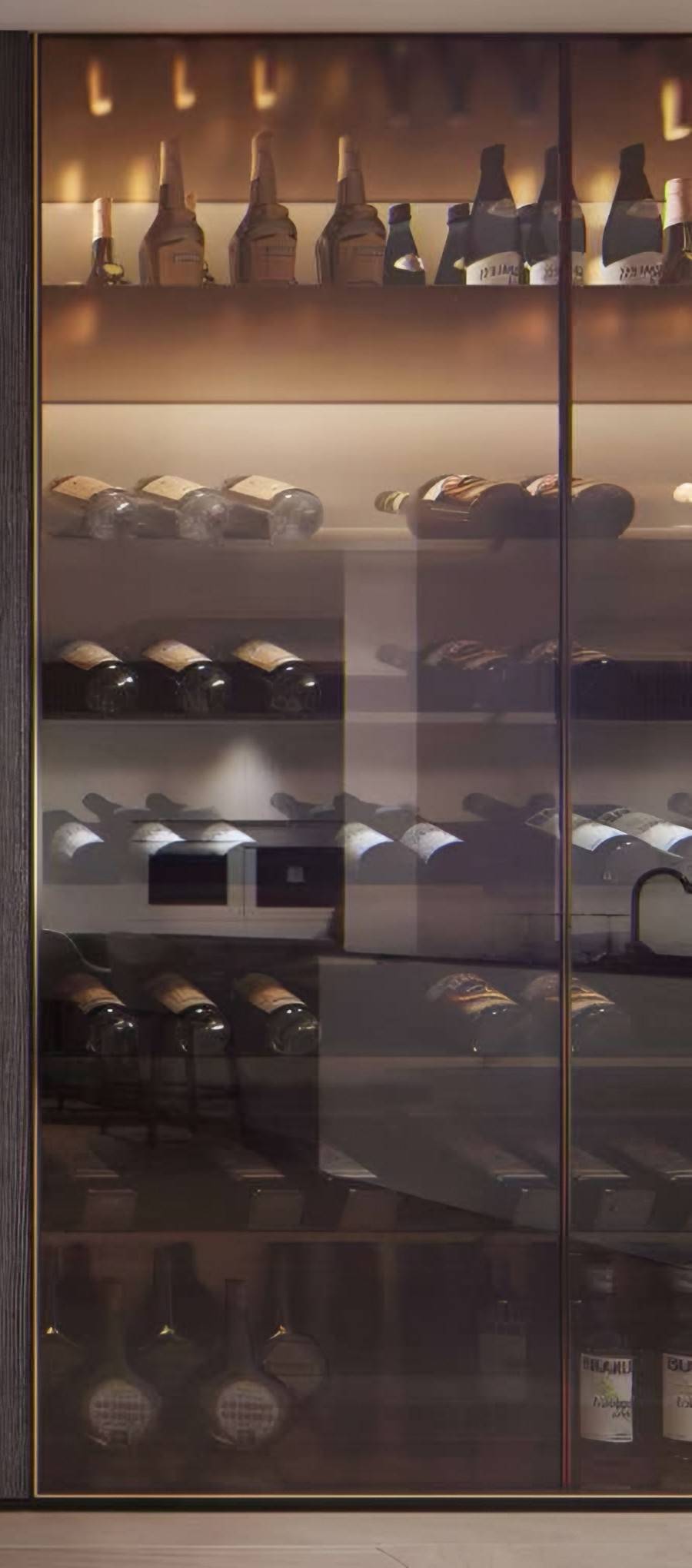 Detail of the lit, glass-fronted wine wall set into dark timber cladding