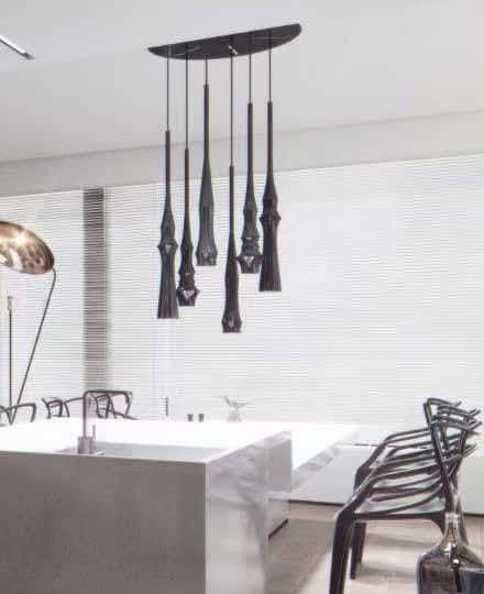 Stone kitchen island beneath a cluster of dark sculptural pendants
