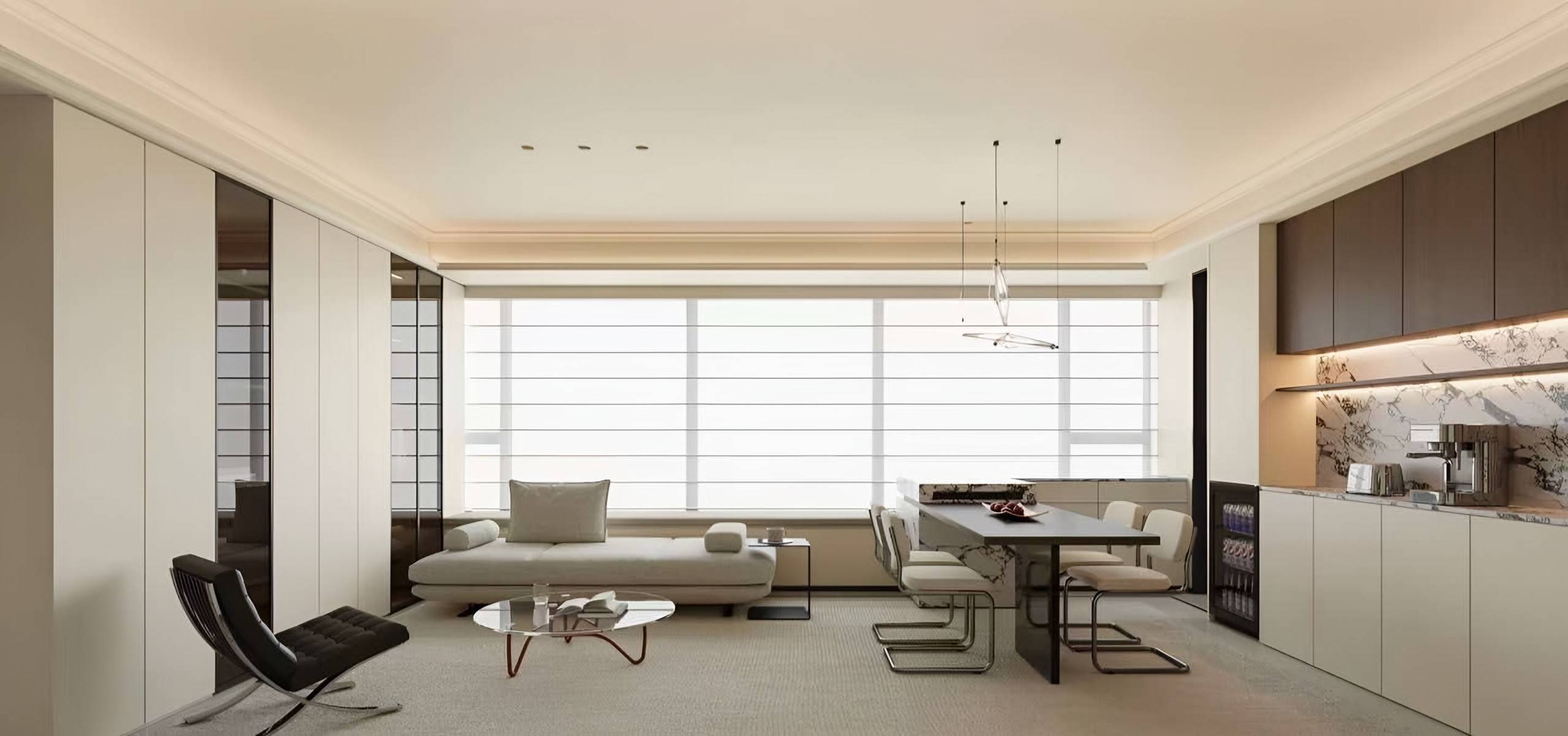 Ivory apartment with a long daybed sofa, a stone-topped dining table, a marble-backed kitchen run and a wall of flush cabinetry